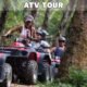 atv tour big buddha temple showing several riders on atv vehicles driving in single file on a dirt road through lush jungle with large trees