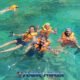 snorkeling tour phi phi with eight participants swimming in the clear blue water wearing orange life jackets and masks and snorkels