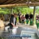 bukit elephant park staff member cleans food preparation table in shaded hut while several tourists stand around watching