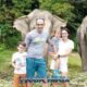 tourist couple with two children posing in front of three elephants at bukit elephant park