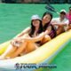 canoe tour in phangnga bay with three participants sitting in a yellow sea canoe with a canoe guide in a pink shirt paddling