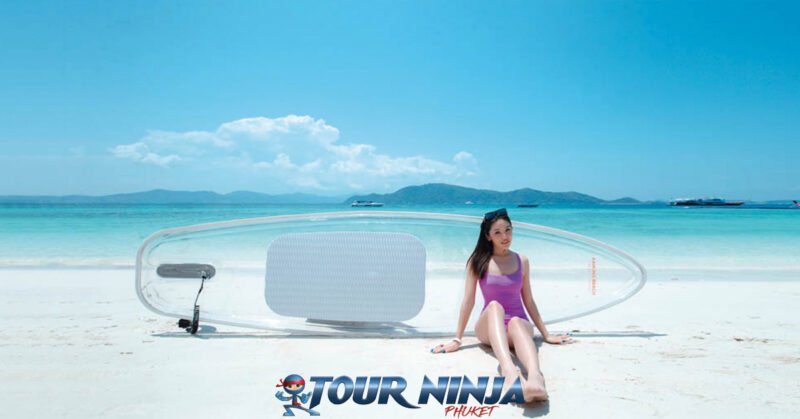 coral-island-daytrip-beach-n5 coral island beautiful white beach with young girl sitting in front of a clear paddleboard displayed sideways on the beach