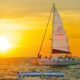 sunset showing sailboat on calm sea on right and beautiful white setting sun in yellow sky