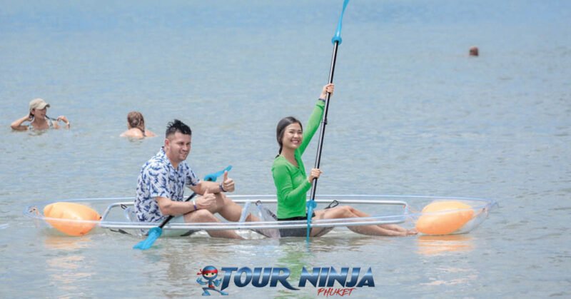 daytrip-phangnga-bay-s4 clear bottom kayak with two tourists paddling in the sea with two other tourists swimming in the background