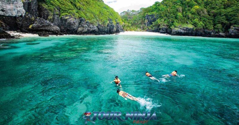 daytrip-phiphi-khai-island-s15 phi phi island four tourist wearing orange life jackets snorkeling in the clear blue sea in front of a small beautiful beach