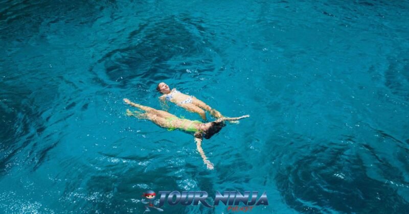daytrip-racha-islands-snorkeling-s2 racha islands with two female swimmers in colorful bikinis floating in the crystal clear sea enjoy their trip