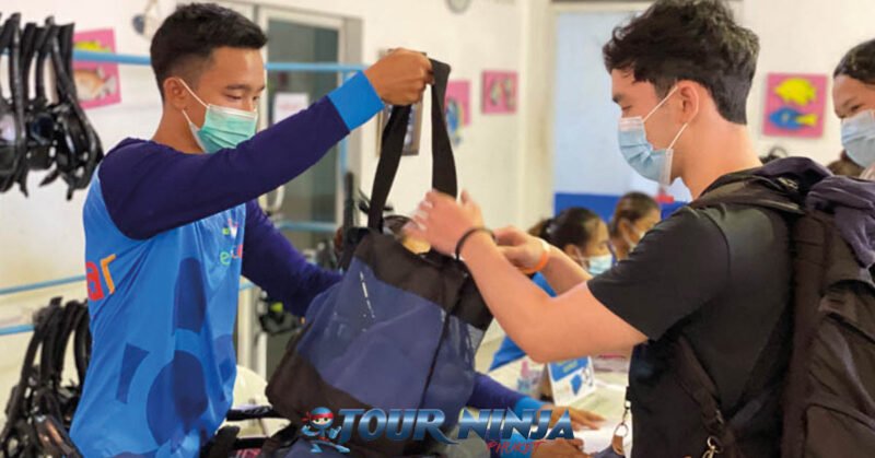 daytrip-similan-island-snorkeling-s2 customer receiving a gearbag with snorkeling equipment for his similan island daytrip by a young asian guy wearing a blue shirt