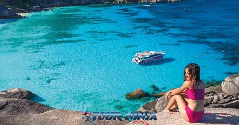 daytrip-snorkeling-similan-island-s10 similan island donald duck bay viewpoint an asian female in pink swimsuit sitting on a rock being photographed with the bay behind