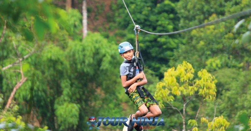 family-friendly-zipline-tours-phuket-pp1 adventure zipline activity in phuket with a young boy wearing a light blue safety helmet gliding through the jungle