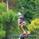 adventure zipline activity in phuket with a young boy wearing a light blue safety helmet gliding through the jungle