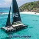 hype catamaran classic aerial view showing black sails in clear turquoise bay with white beach and island shown