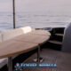 hype luxury cruising yacht showing white sofas with wooden table on timber deck with stairwell and calm ocean in the background