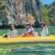 kayak tour visiting phangnga bay with three participants and a tour guide in a yellow inflatable kayak paddling