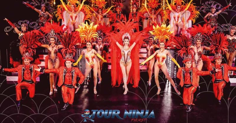 phuket-simon-cabaret-ladyboy-show simon cabaret phuket with a large group of ladyboy dancers dressed in red and orange costumes with hats and feathers