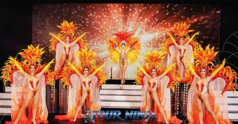 simon-cabaret-ladyboy-show-phuket simon cabaret phuket with a group of seven ladyboy dancers dressed in yellow and orange costumes with wings and feathers on stage