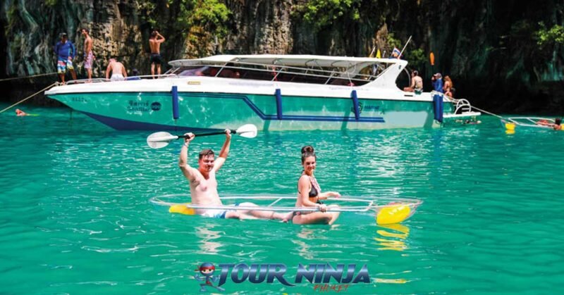 snorkeling-kayaking-phiphi-island-s4 phi phi islands with a couple sailing in a clear kayak next to a white speedboat moored up in pileh lagoon