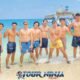 snorkeling with a group of nine young males posing for a group photo on a beach with the sea as a backdrop