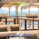 comfortable white balcony sofas on sunset terrace of yona beach club with cabanas and blue sea in background